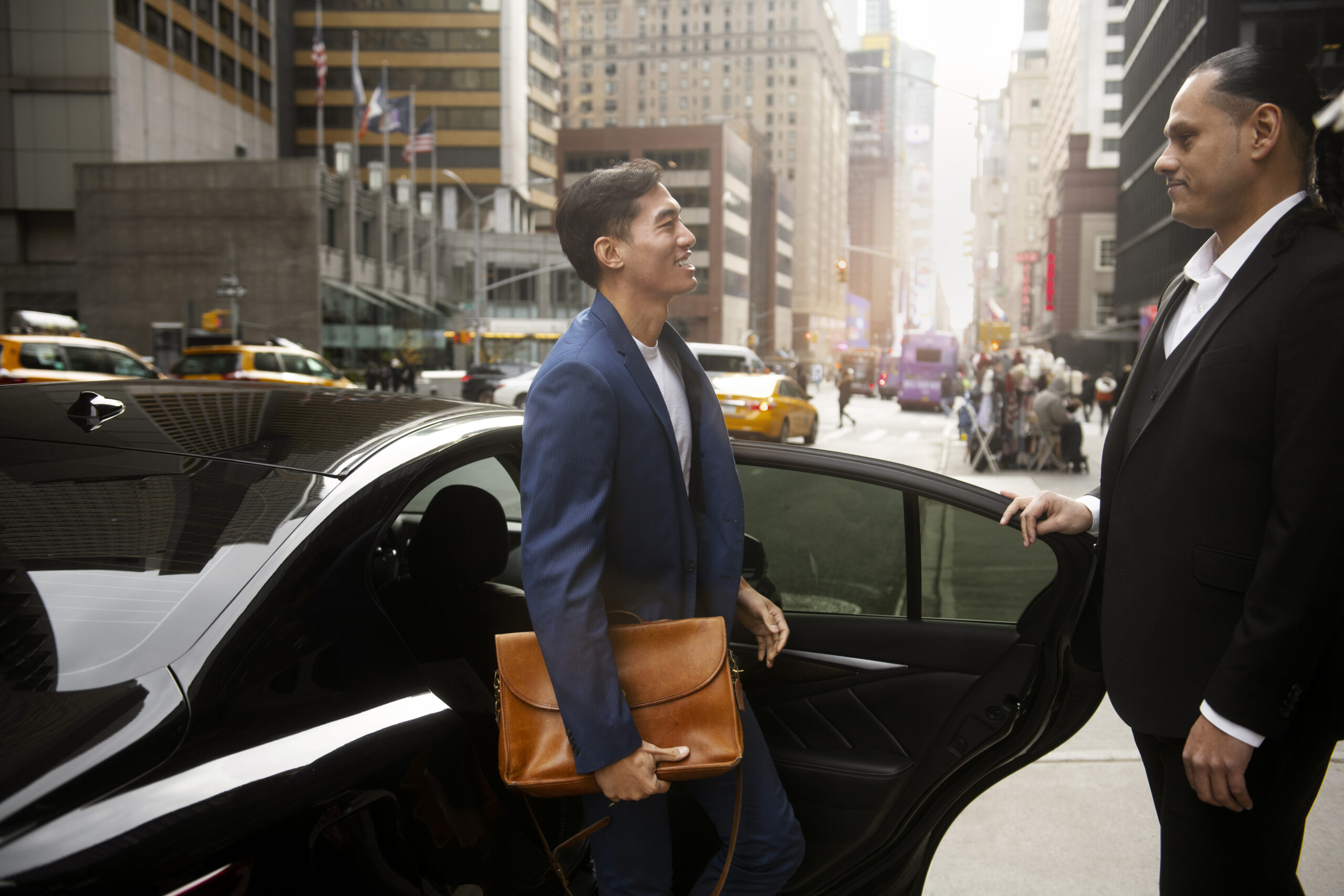 Professional chauffeur assisting passenger with car door