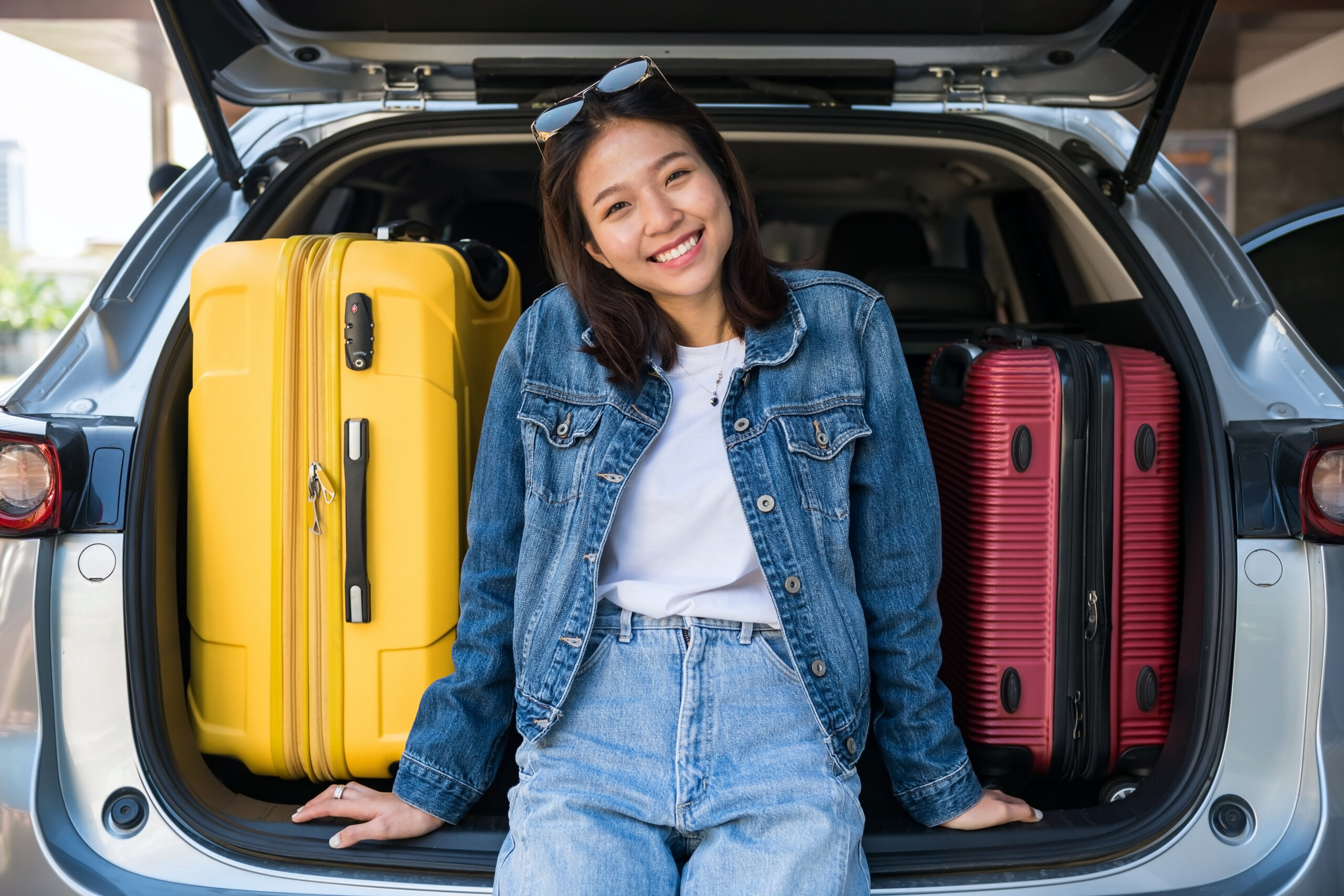 Traveler with suitcases sitting on a car, symbolizing Mobile Butlers Intercity Transfers for convenient city-to-city travel