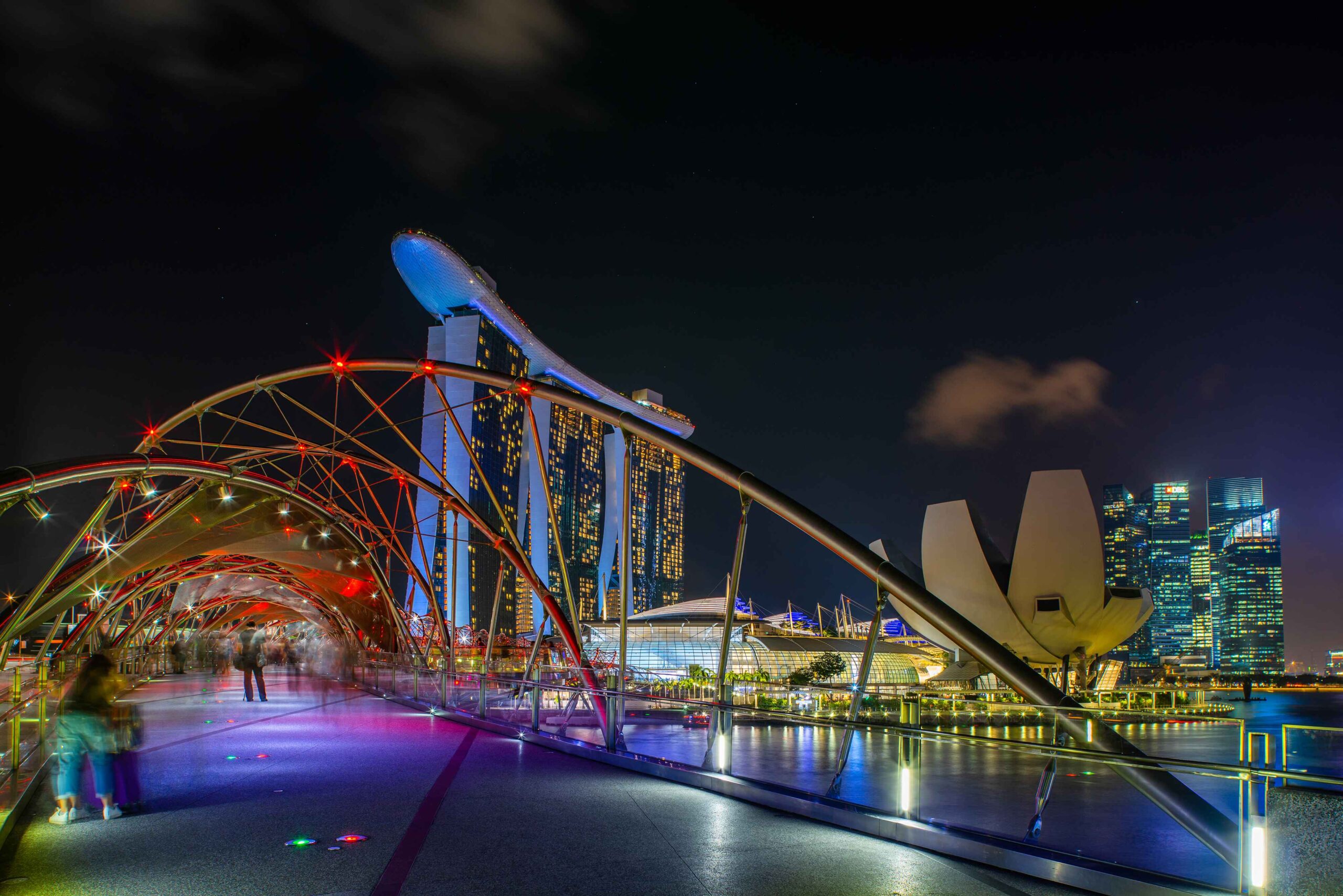 A night view from Singapore's Helix Bridge looking towards the illuminated Marina Bay Sands hotel