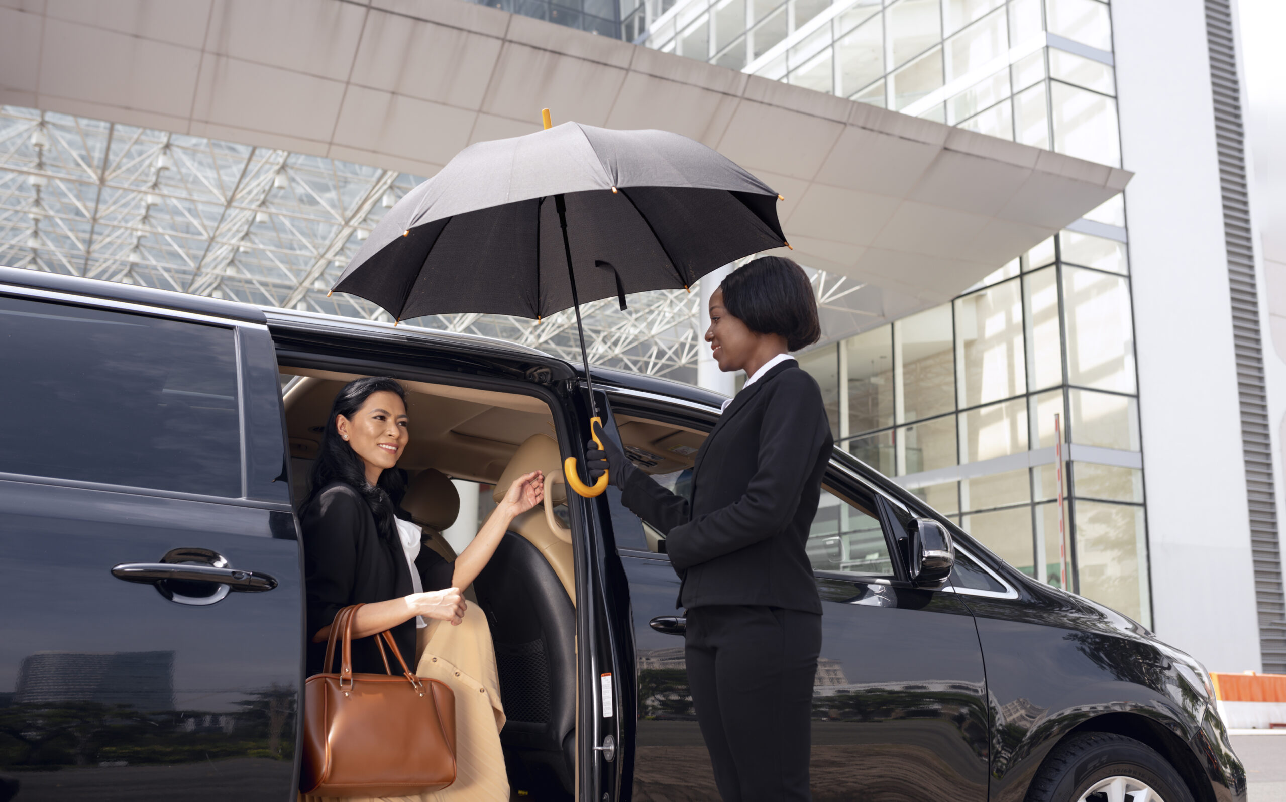 A businesswoman getting out of the cab with the assistance of a chauffeur