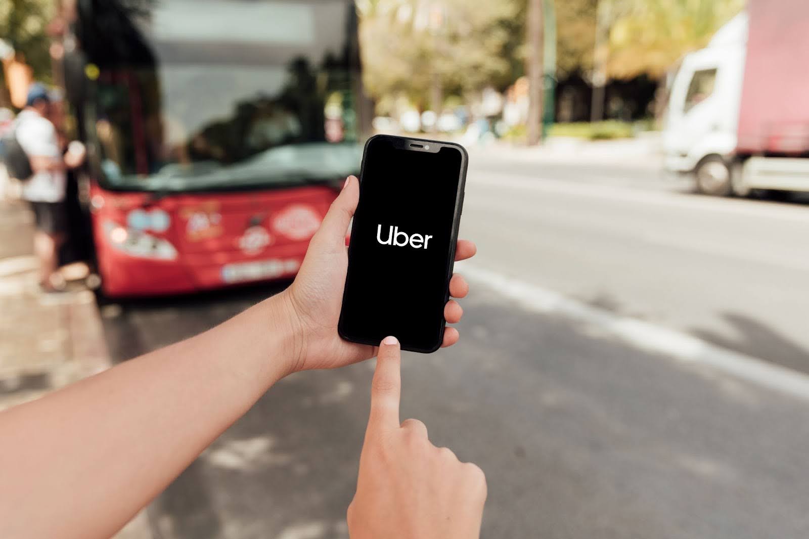 Close-up of hands holding a smartphone displaying the Uber logo